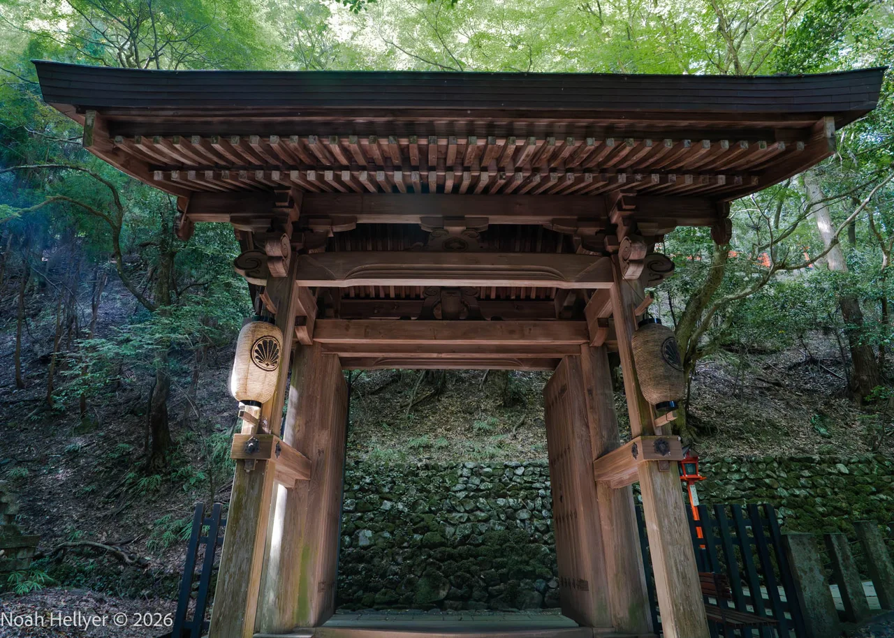 The weathered wooden gate of Yuki-jinja shrine framed by cedar forest.